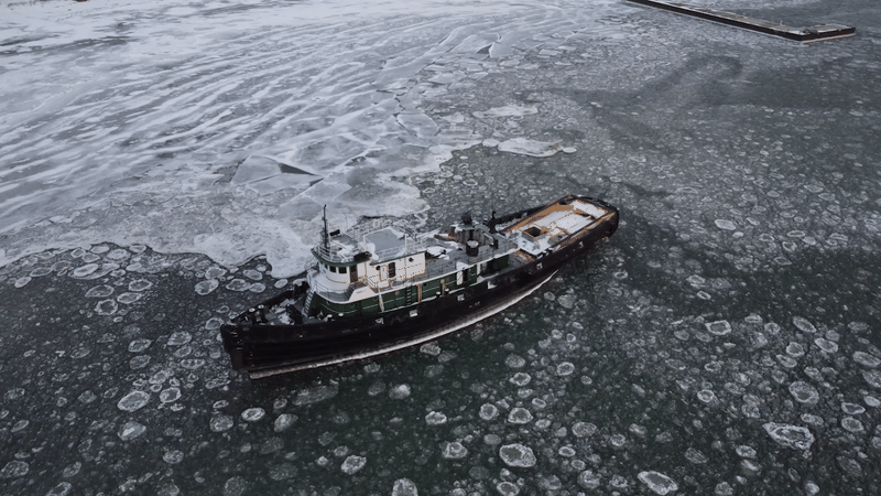 Arial view of a ship in icy, moving waters on a gray day.