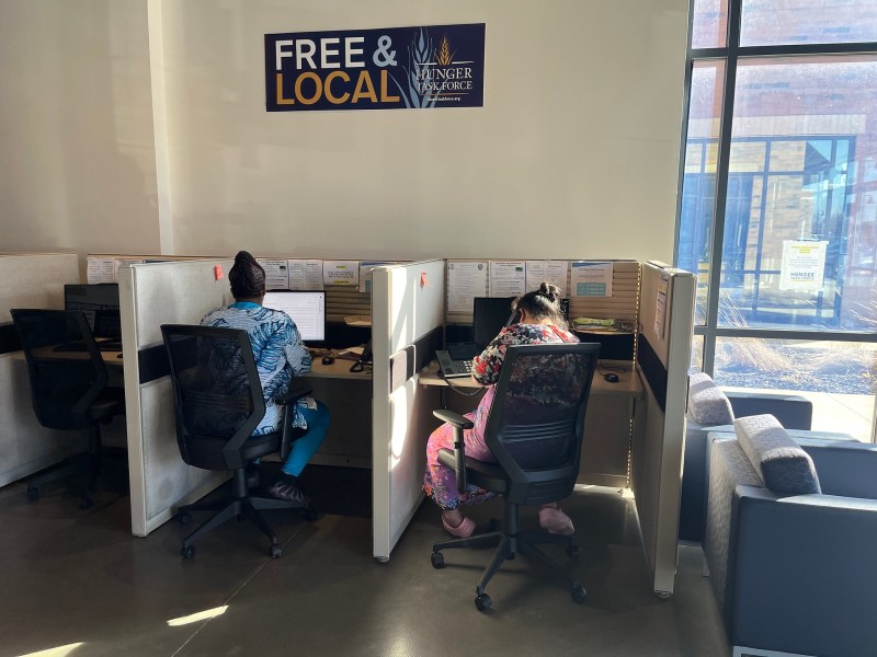 Two people in cubicles under a "FREE & LOCAL" sign on the wall