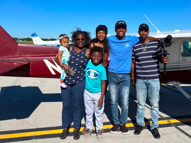 Family poses in front of small airplane.
