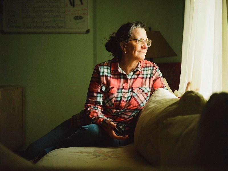 Woman sits and looks out window.