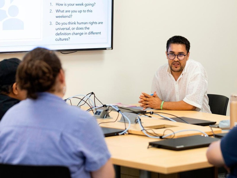 Man at desk talks to others