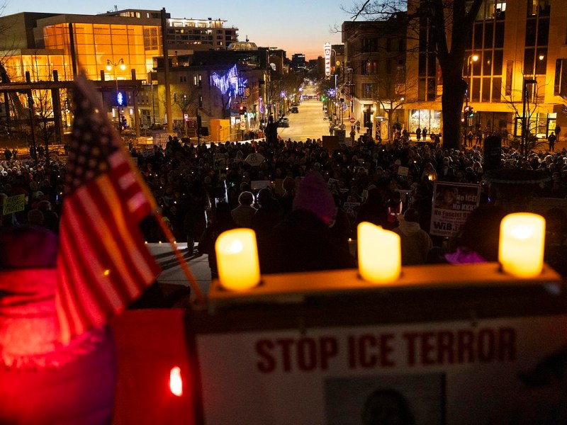 Candles and an American flag are foreground a scene of Madison cityscape at twilight.