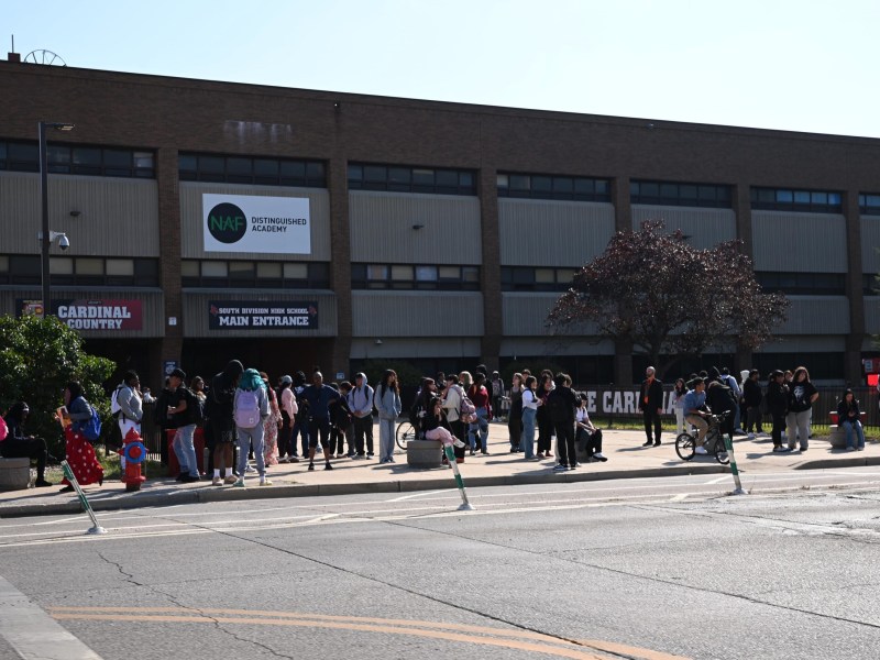 People on a sidewalk outside South Division High School main entrance